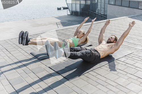 Image of Fit fitness woman and man doing fitness exercises outdoors at city