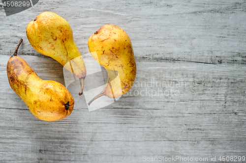 Image of yellow pears on white wooden background, top view.