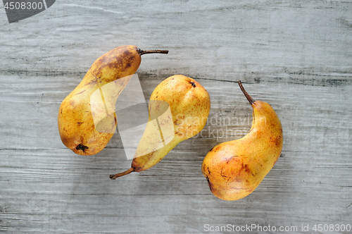 Image of yellow pears on white wooden background, top view.