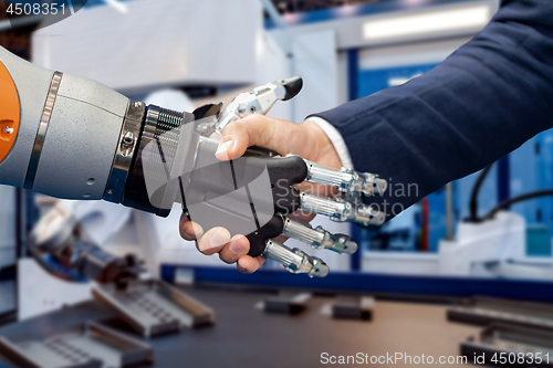 Image of Hand of a businessman shaking hands with a Android robot.