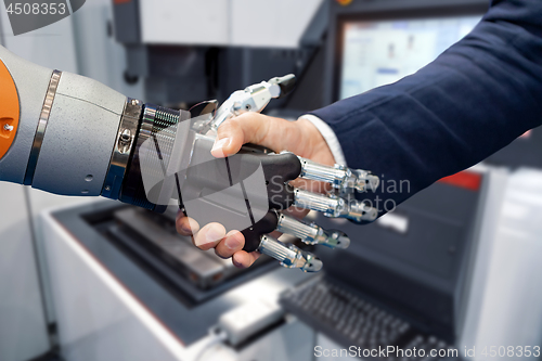 Image of Hand of a businessman shaking hands with a Android robot.