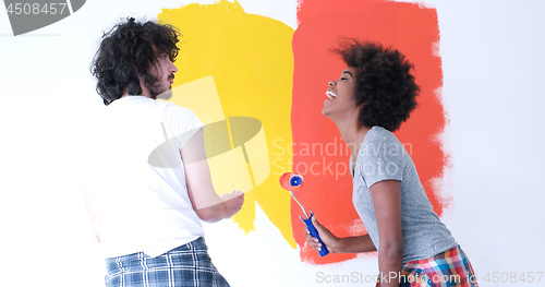 Image of multiethnic couple painting interior wall