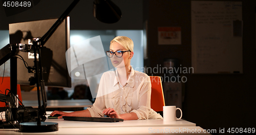 Image of woman working on computer in dark office