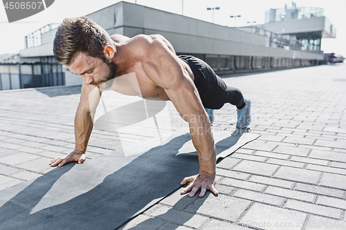 Image of Fit fitness man doing fitness exercises outdoors at city