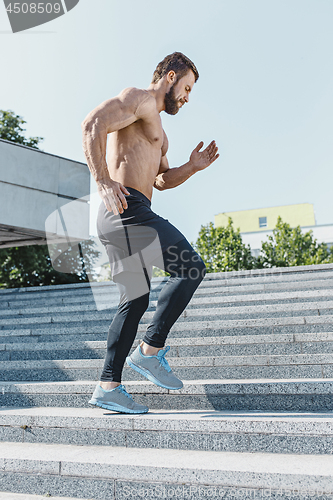 Image of Fit man doing exercises outdoors at city