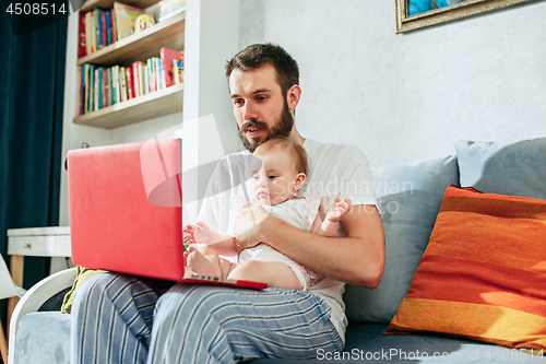 Image of Proud father holding his baby daughtesr at home