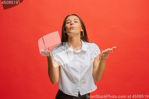 Image of Beautiful female half-length portrait isolated on red studio backgroud. The young emotional surprised woman