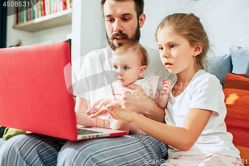 Image of Proud father holding his baby daughters at home