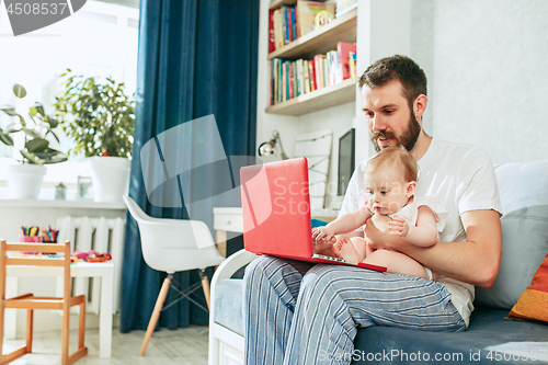 Image of Proud father holding his baby daughtesr at home