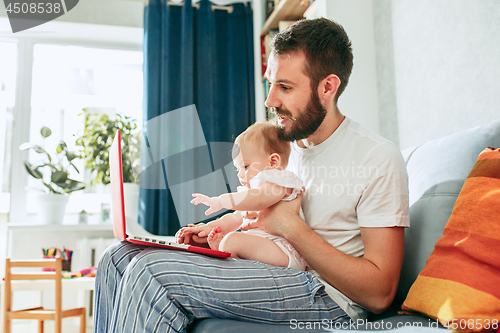 Image of Proud father holding his baby daughtesr at home