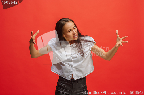 Image of Portrait of an angry woman looking at camera isolated on a red background