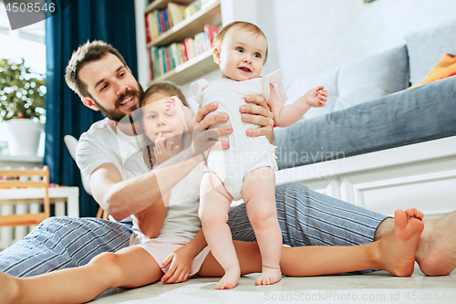 Image of Proud father holding his newborn baby daughter at home