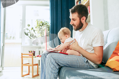 Image of Proud father holding his baby daughtesr at home