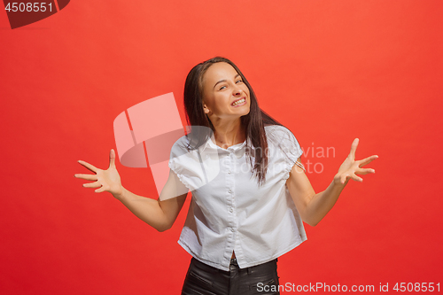 Image of Beautiful female half-length portrait isolated on red studio backgroud. The young emotional surprised woman