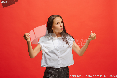 Image of Portrait of an angry woman looking at camera isolated on a red background