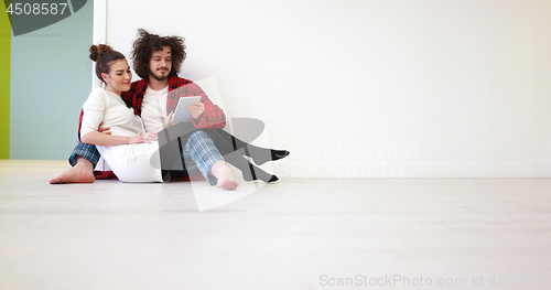 Image of Young Couple using digital tablet on the floor