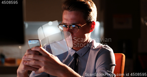 Image of man using mobile phone in dark office