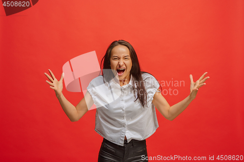 Image of The young emotional angry woman screaming on red studio background