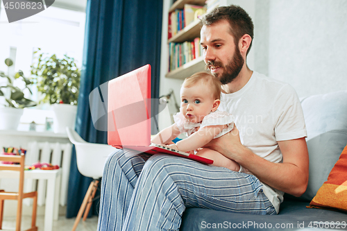 Image of Proud father holding his baby daughtesr at home