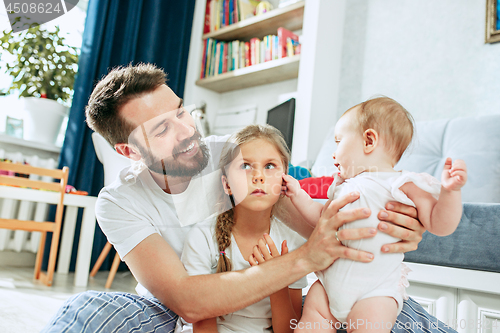 Image of Proud father holding his newborn baby daughter at home
