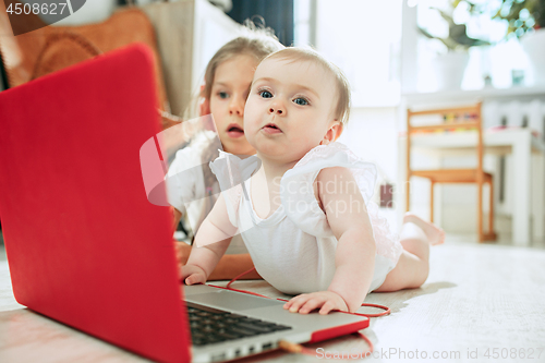 Image of Portrait of little baby girl looking at camera with a laptop