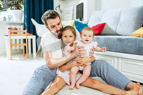 Image of Proud father holding his newborn baby daughter at home