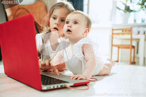 Image of Portrait of little baby girl looking at camera with a laptop