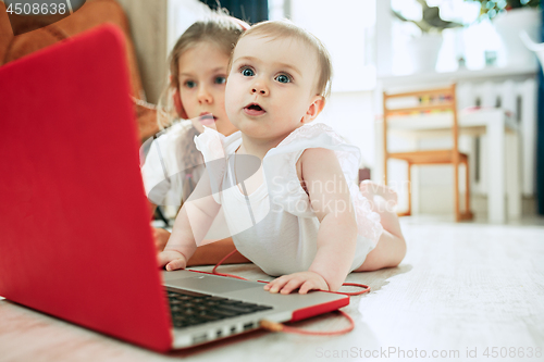 Image of Portrait of little baby girl looking at camera with a laptop