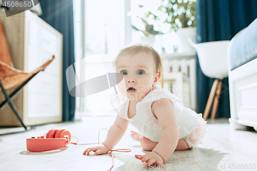 Image of Cute young baby sitting on the floor at home playing with headphones