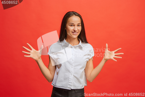 Image of The happy business woman standing and smiling against red background.