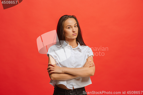 Image of The serious business woman standing and looking at camera against red background.