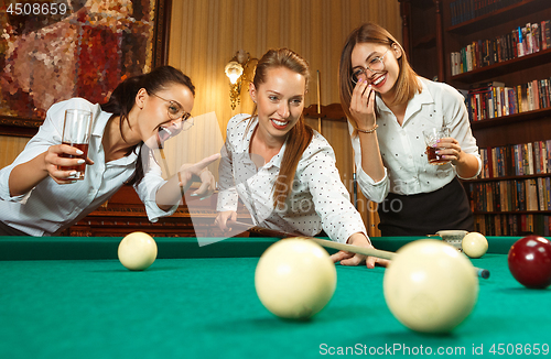 Image of Young women playing billiards at office after work.