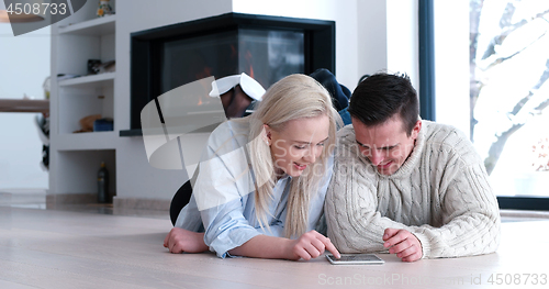 Image of Young Couple using digital tablet on the floor