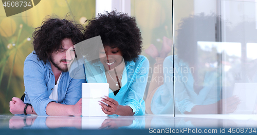 Image of Couple relaxing together at home with tablet computer