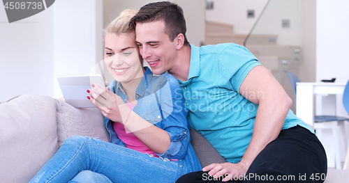 Image of couple relaxing at  home with tablet computers