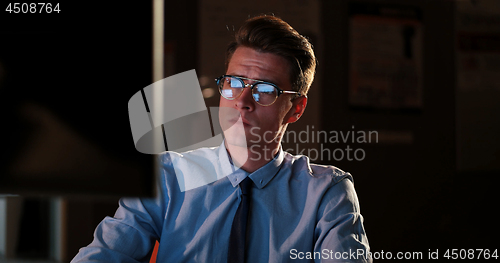 Image of man working on computer in dark office