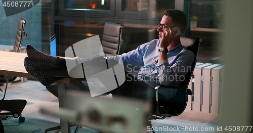 Image of businessman sitting with legs on desk at office