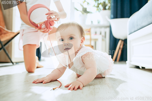 Image of Cute young baby sitting on the floor at home playing with headphones