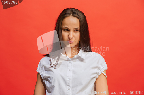 Image of The serious business woman standing and looking at camera against red background.