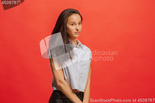 Image of The serious business woman standing and looking at camera against red background.