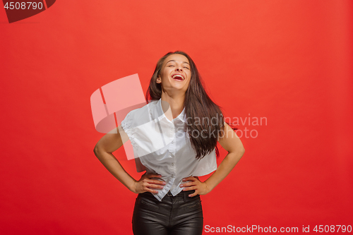 Image of The happy business woman standing and smiling against red background.