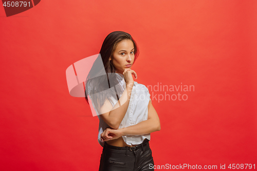 Image of The serious business woman standing and looking at camera against red background.