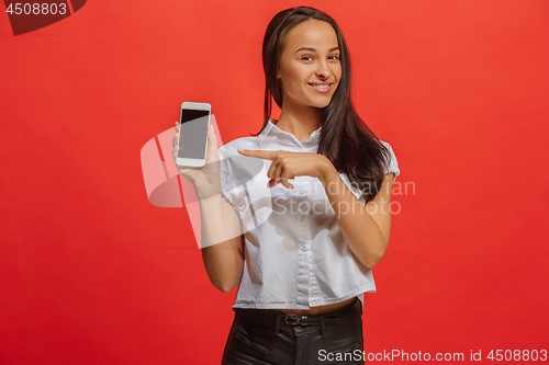 Image of Portrait of a smiling woman in red dress showing blank smartphone screen