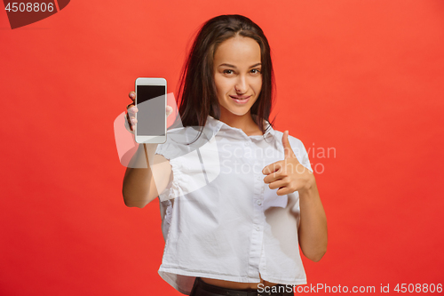 Image of Portrait of a smiling woman in red dress showing blank smartphone screen