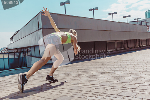 Image of Pretty sporty woman jogging at city