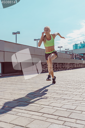 Image of Pretty sporty woman jogging at city