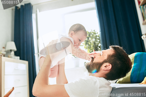 Image of Proud father holding his newborn baby daughter up in the air at home