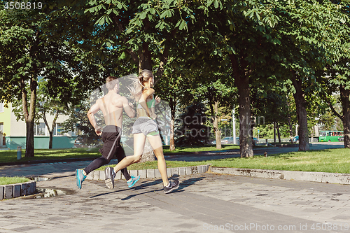 Image of Pretty sporty woman and man jogging at city