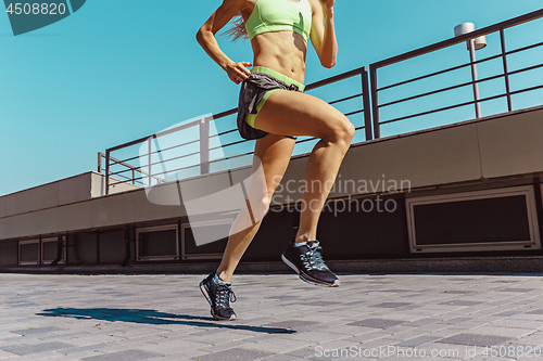 Image of Pretty sporty woman jogging at city