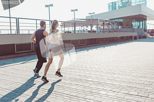 Image of Pretty sporty woman and man jogging at city